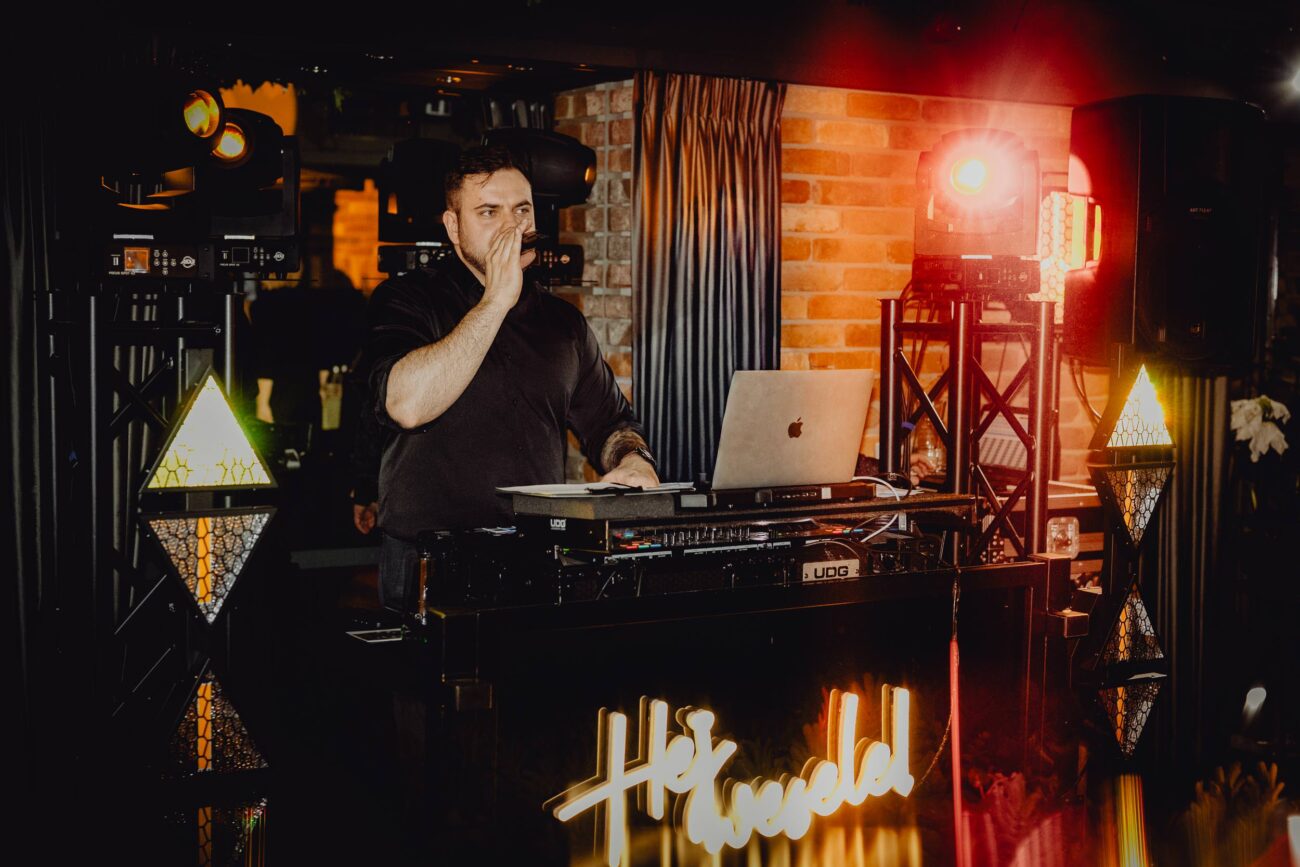 DJ Marcin Siemieniuk z Białegostoku mówi przez mikrofon za swoją konsoletą podczas wesela w Restauracji Kawelin.