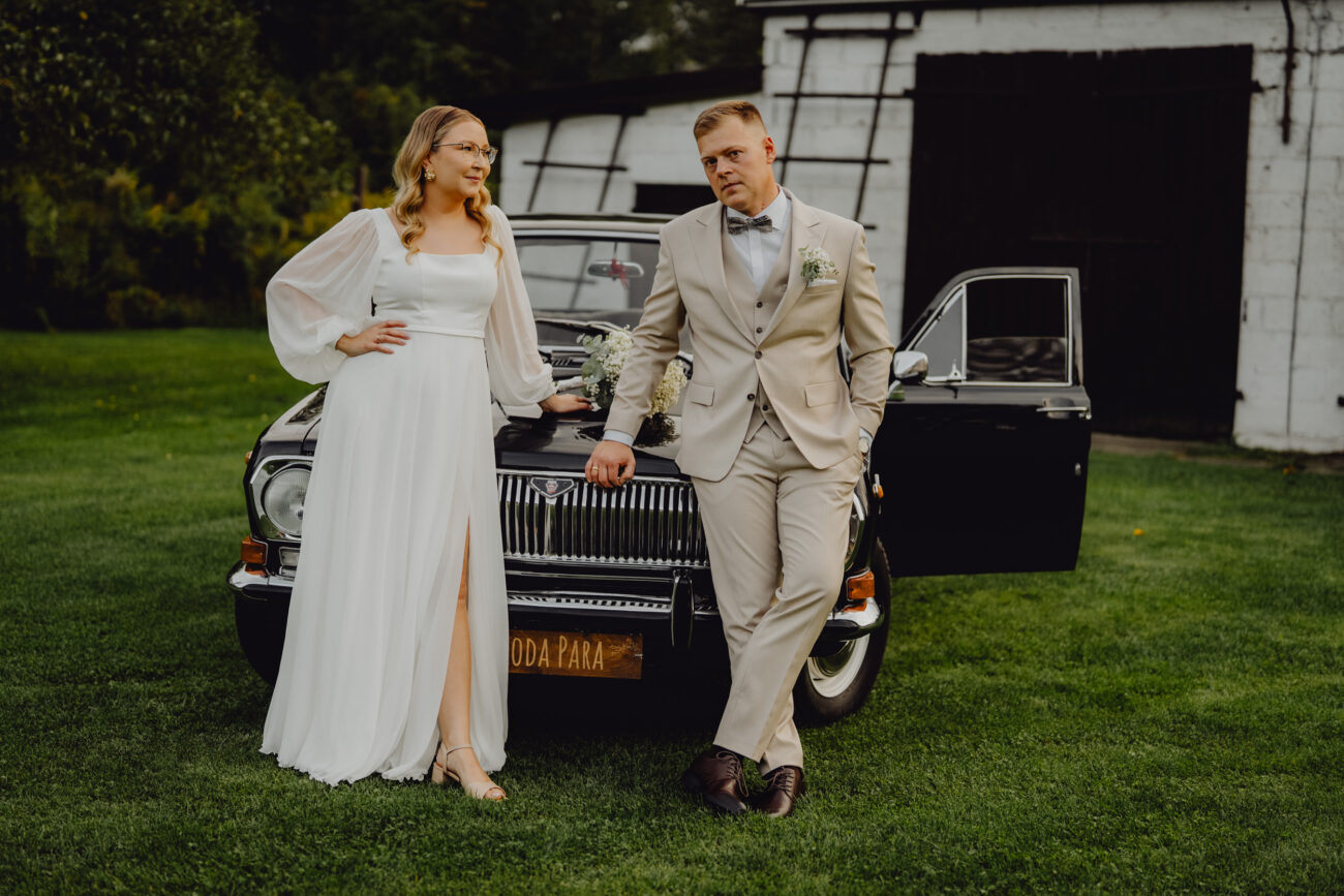 Para Młoda pozuje i opiera się o czarną Wołgę.