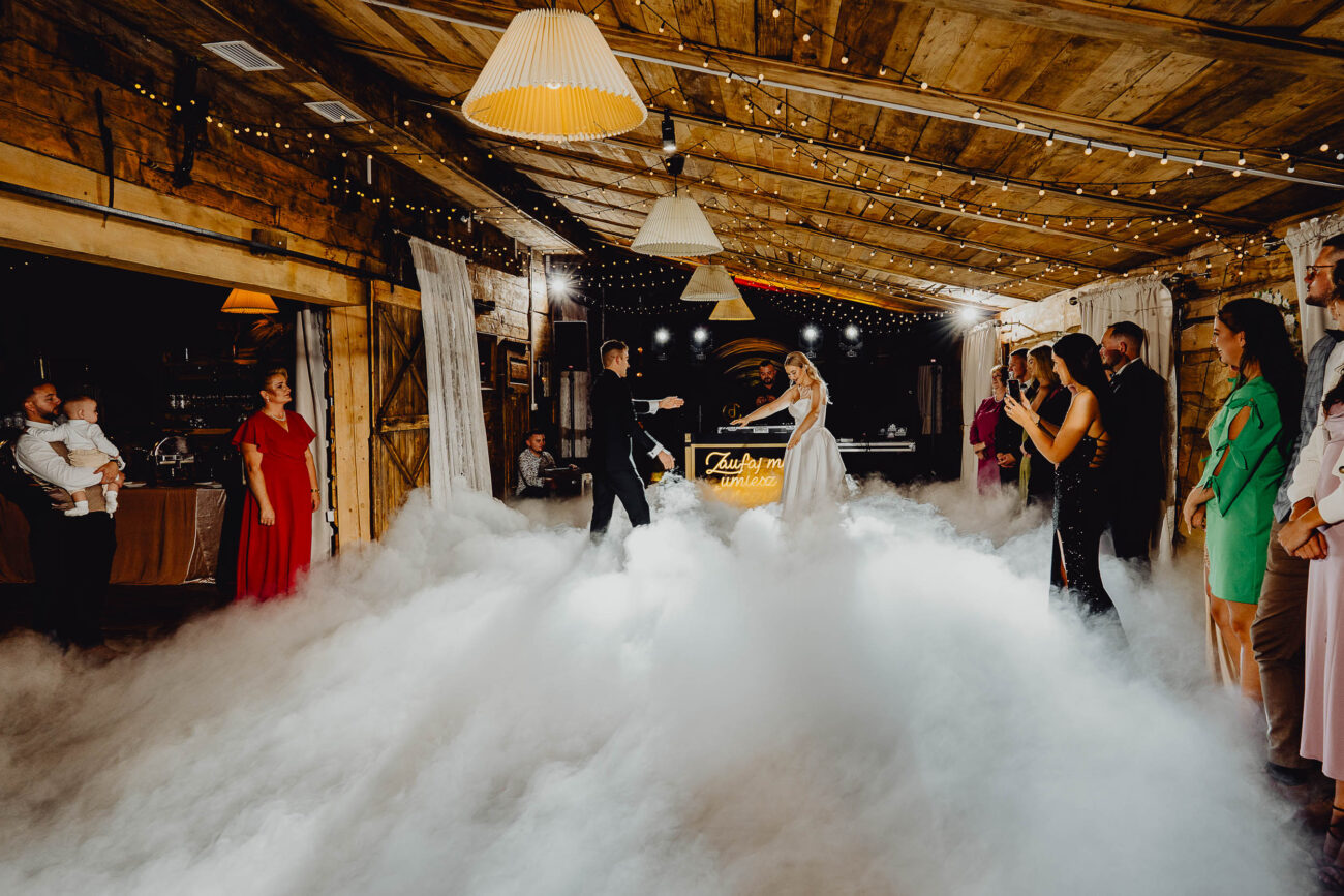 Para Młoda tańczy swój 1 taniec w Dworku Rustyklanym Majątku Howieny. Widać ciężki dym i świetne oświetlenie DJ-a.