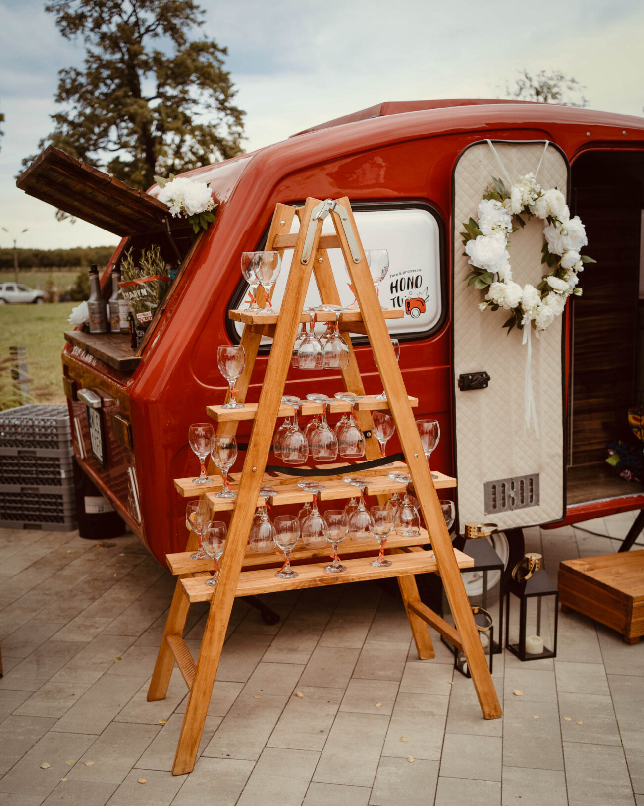 Fotoprzyczepa HONOTU ze stojącym obok stojakiem na kieliszki Prosecco.