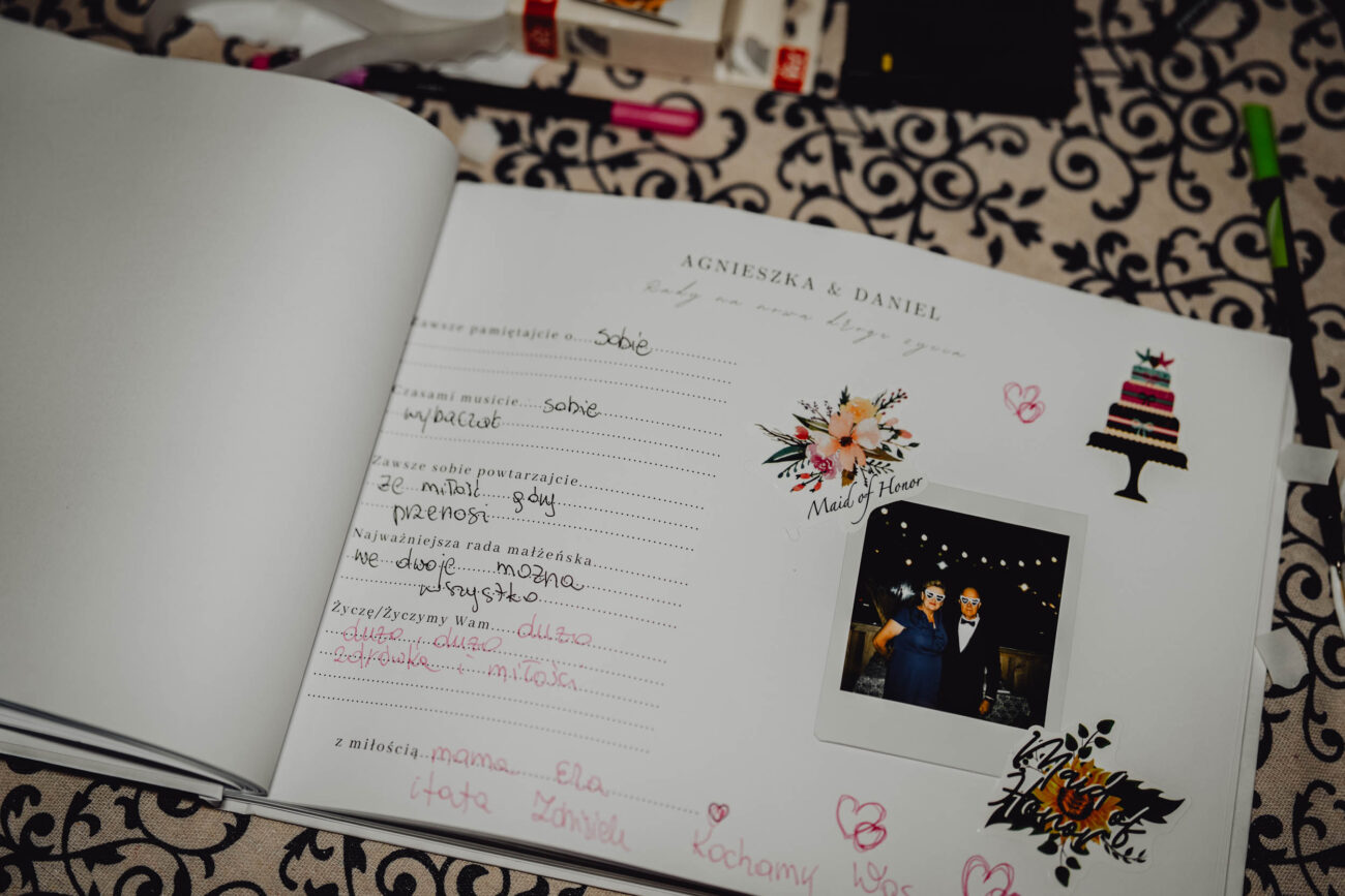 Otwarta księga gości z wpisanymi życzeniami i wklejonym zdjęciem z instaxa.