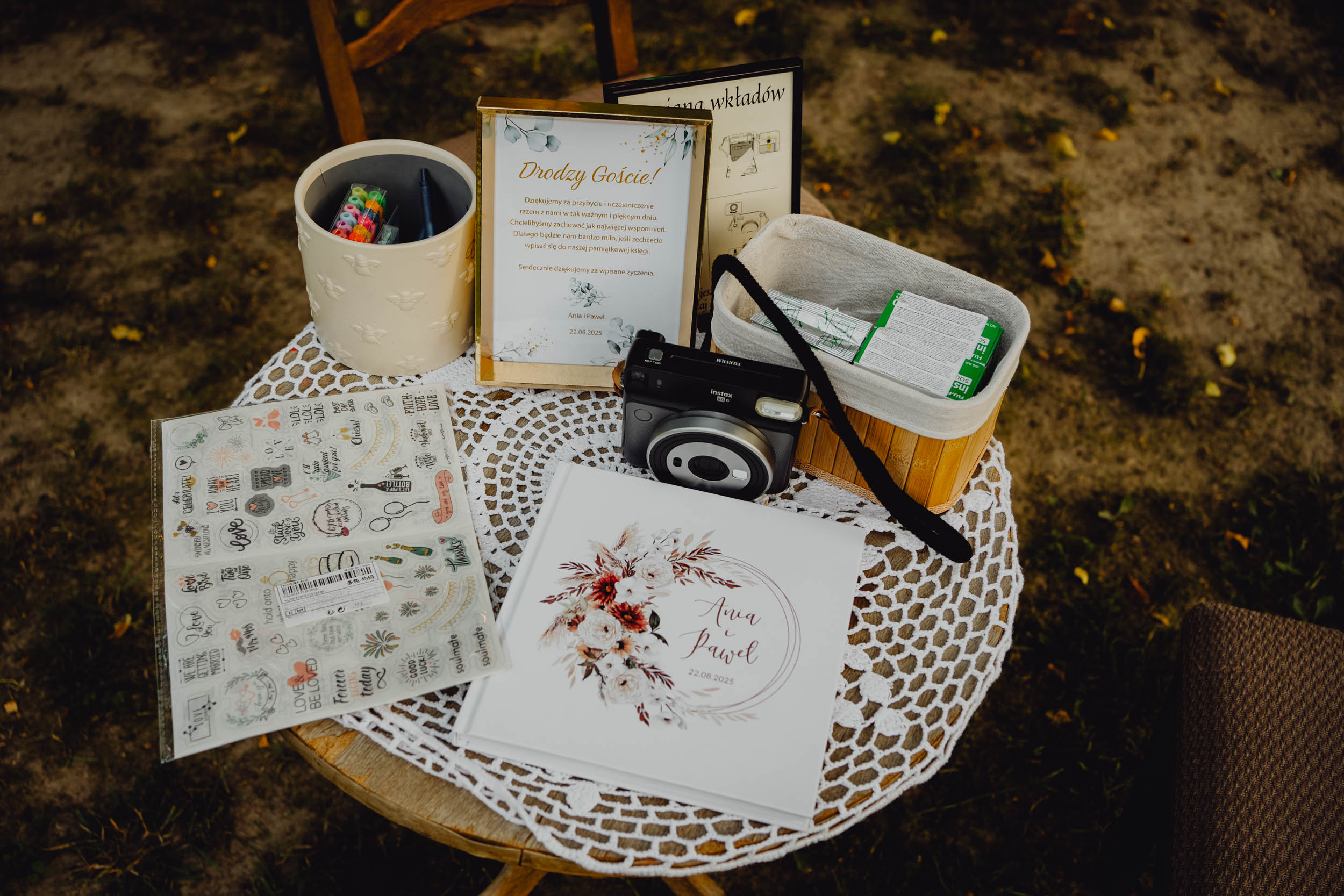 Instax na weselnym stoliku z księgą gości i gadżetami do zdjęć.