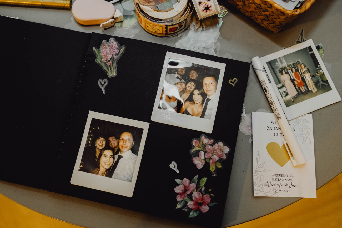 Otwarta księga gości z wpisanymi życzeniami i wklejonym zdjęciem z instaxa.