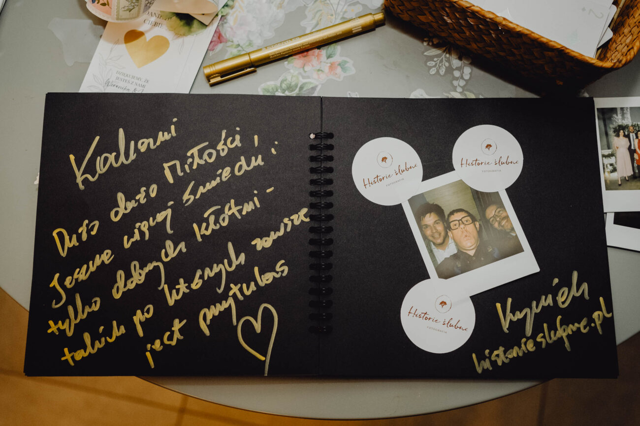 Otwarta księga gości z wpisanymi życzeniami i wklejonym zdjęciem z instaxa.