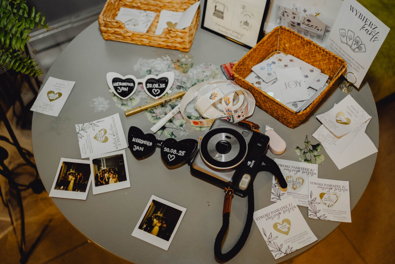 Instax na weselnym stoliku z księgą gości i gadżetami do zdjęć.