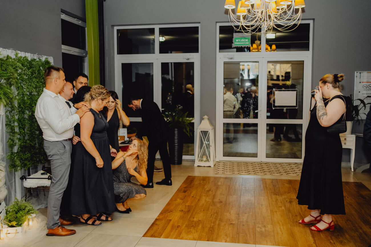 Kobieta robi zdjęcie grupie ludzi aparatem instax na weselu.