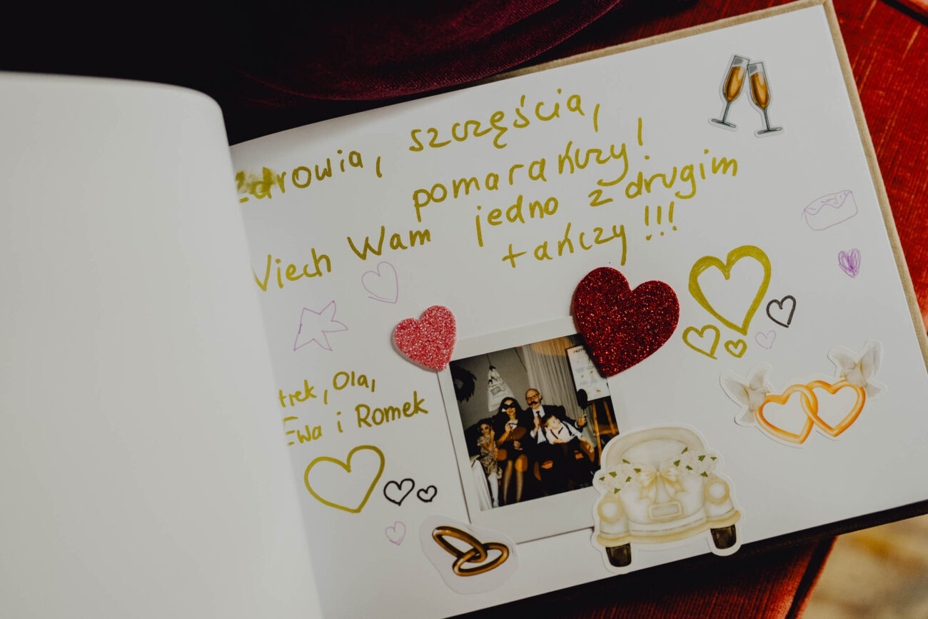 Otwarta księga gości z wpisanymi życzeniami i wklejonym zdjęciem z instaxa.