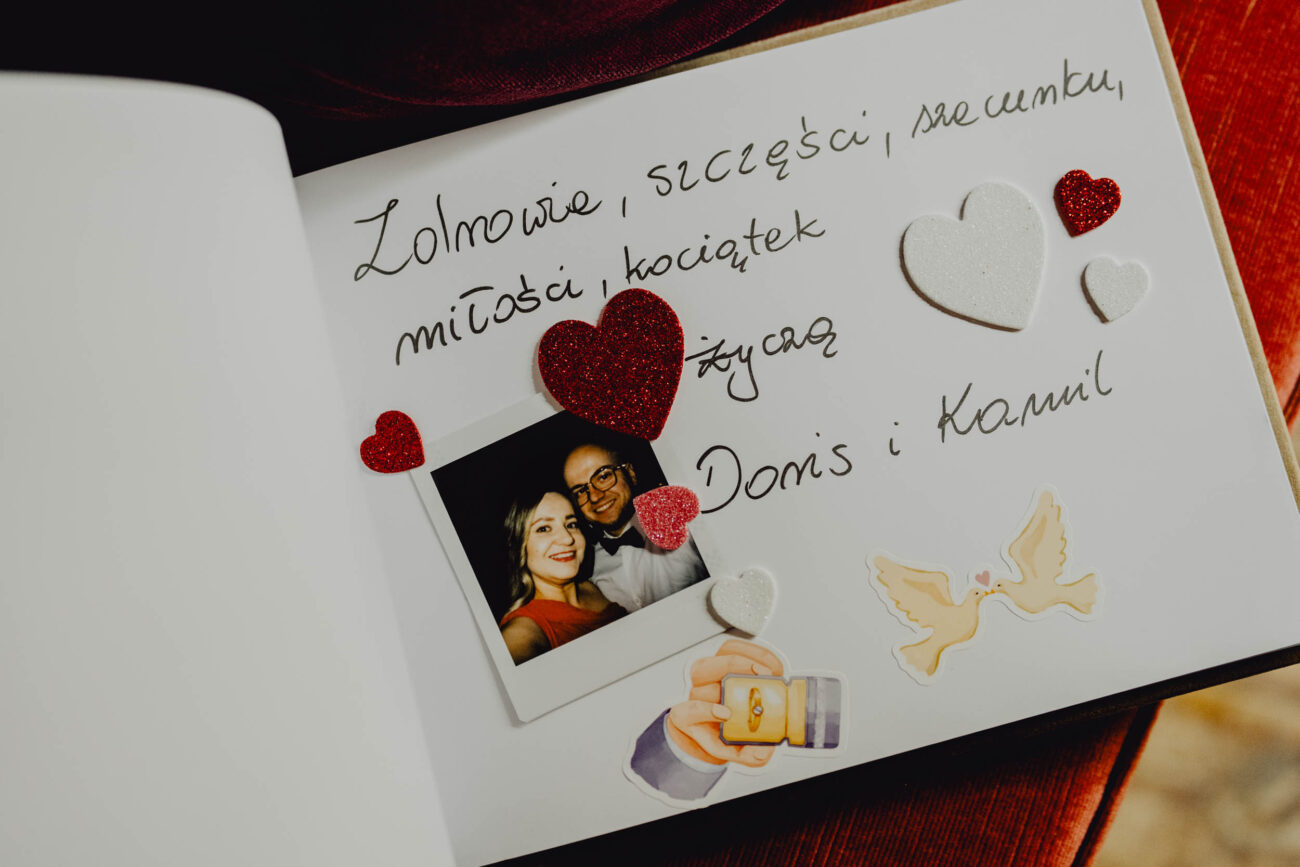 Otwarta księga gości z wpisanymi życzeniami i wklejonym zdjęciem z instaxa.