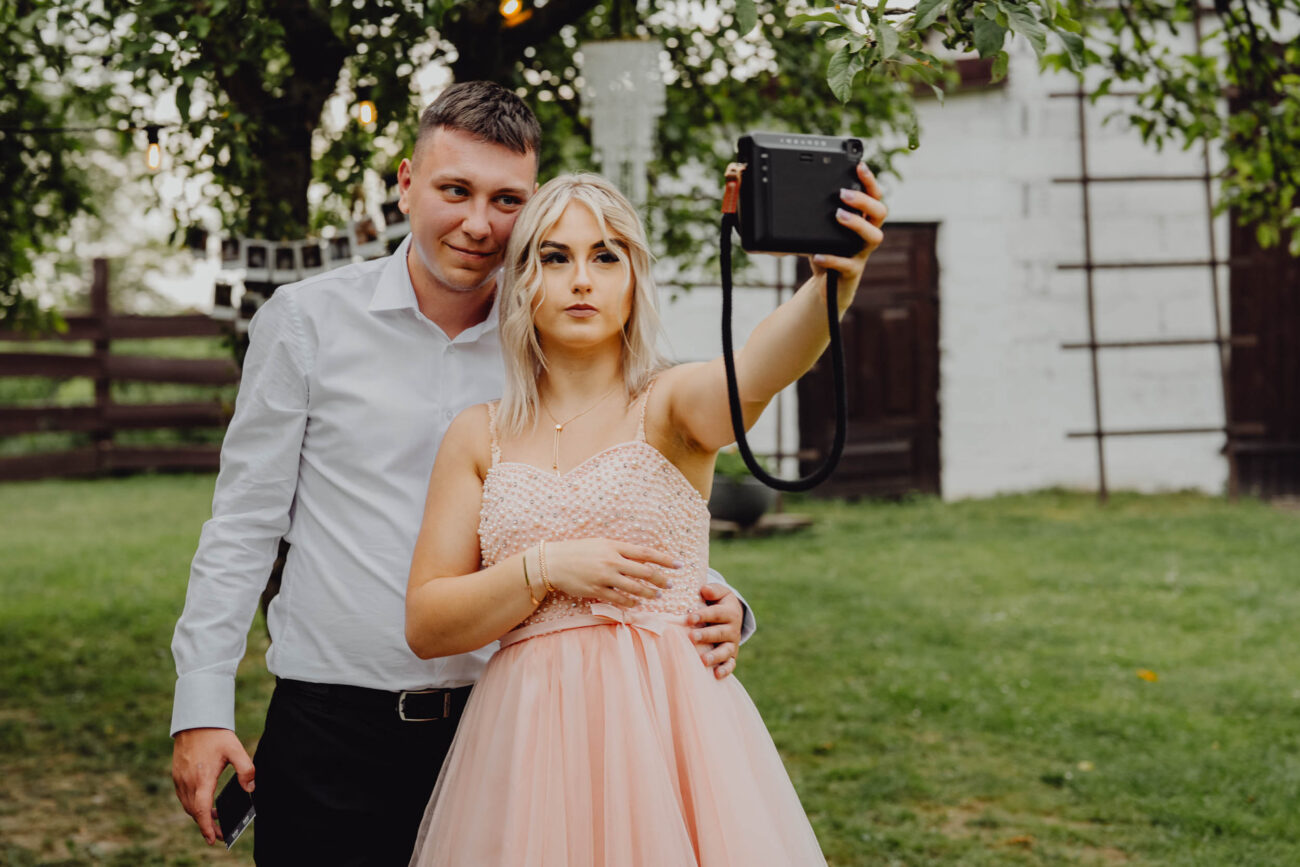 Para robi sobie selfie instaxem na weselu.